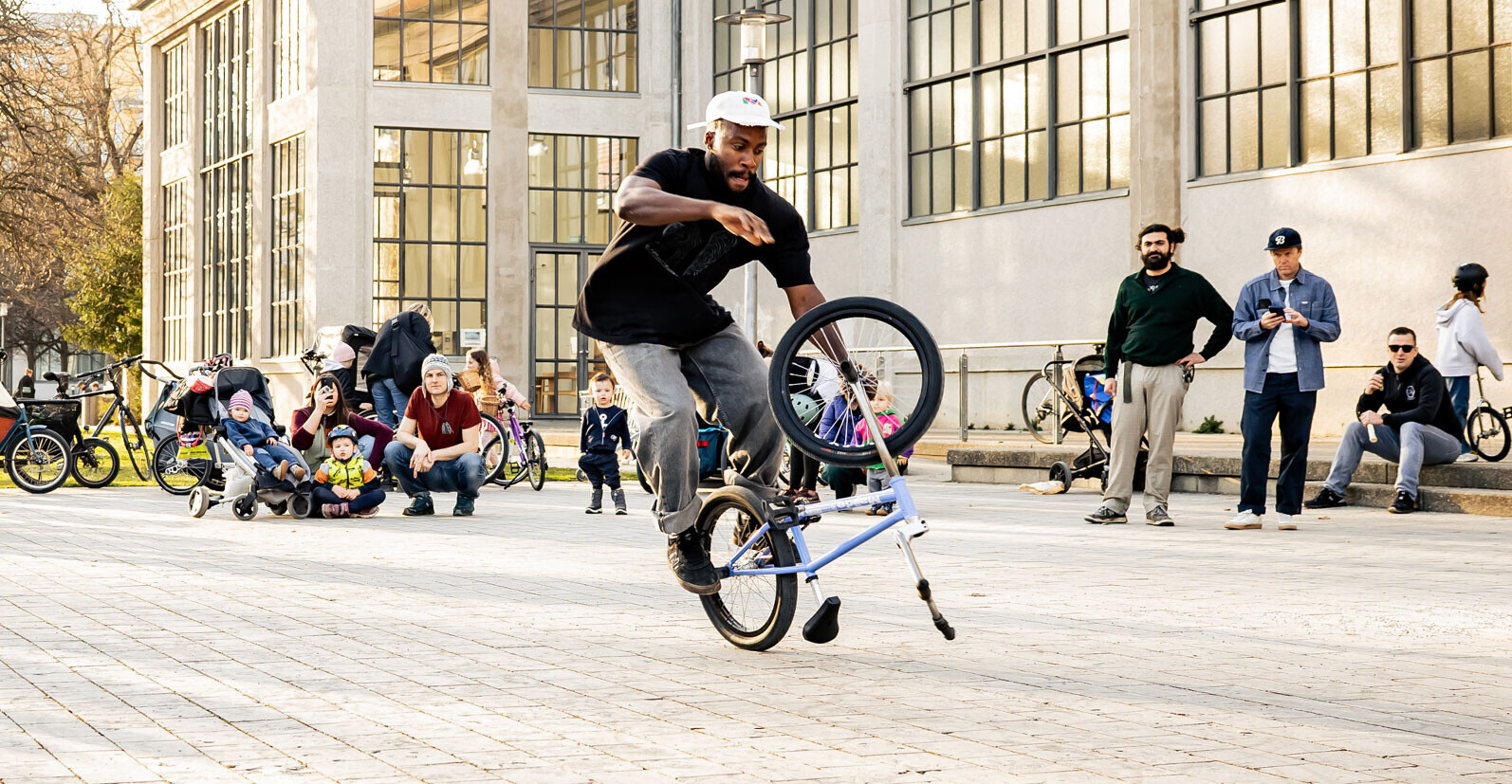 Omari Cato f&uuml;hrt vor Publikum auf einem st&auml;dtischen Platz einen Flatland-BMX-Trick vor.